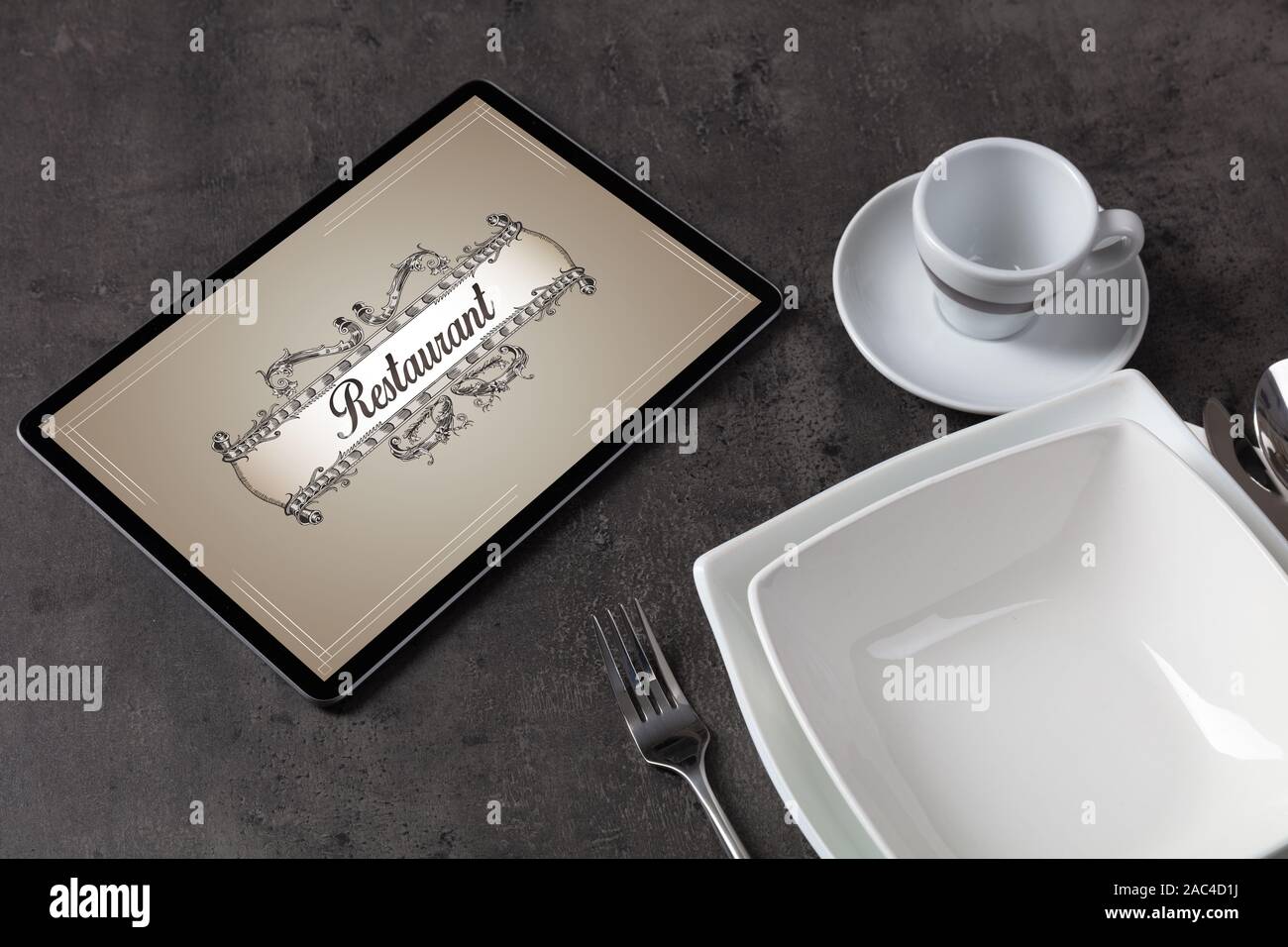 Tablet with stylish restaurant logo and laid table Stock Photo