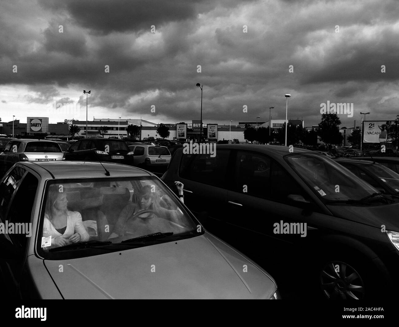 AJAXNETPHOTO. GLISY, FRANCE. - RAIN CLOUDS APPROACHING - TWO PEOPLE ENGAGED IN CONVERSATION IN A CAR IN AN OUT OF TOWN RETAIL SITE CAR PARK.PHOTO:JONATHAN EASTLAND/AJAX REF:GR121506 BW3638 Stock Photo