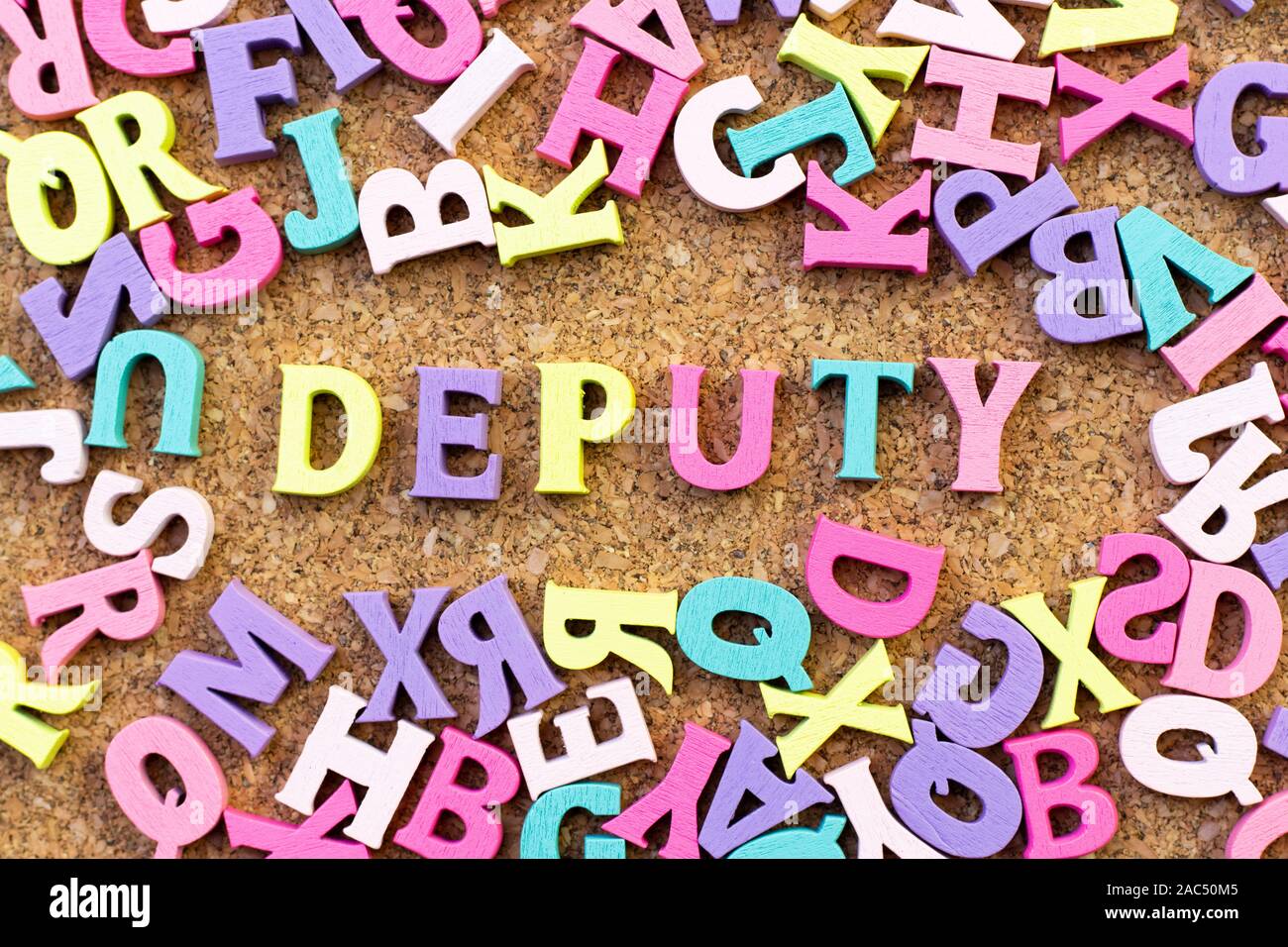 Color alphabet in word deputy with another letter as frame on cork board background Stock Photo