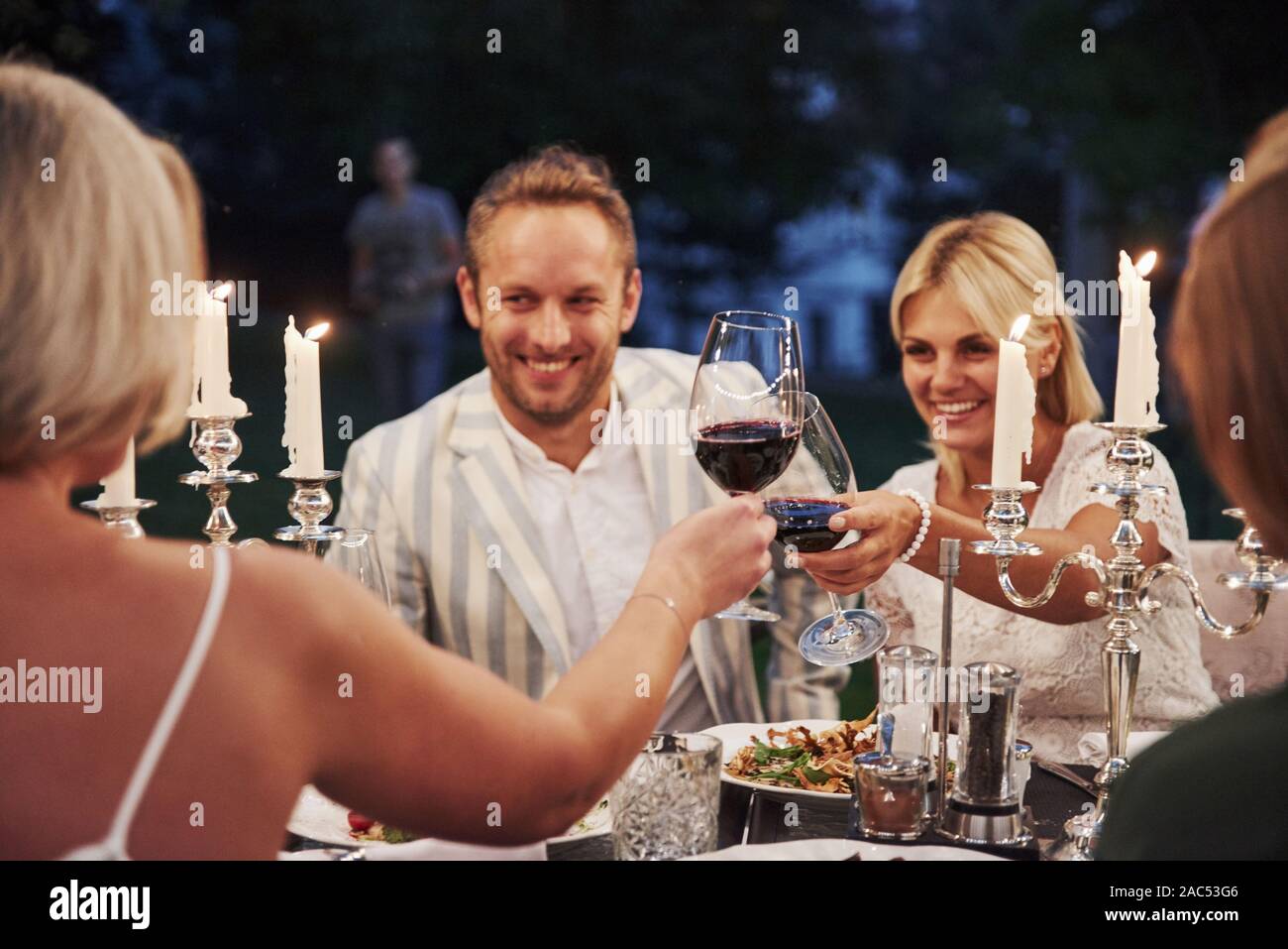 Smiling and good mood. Group of friends in the elegant wear have luxury dinner Stock Photo