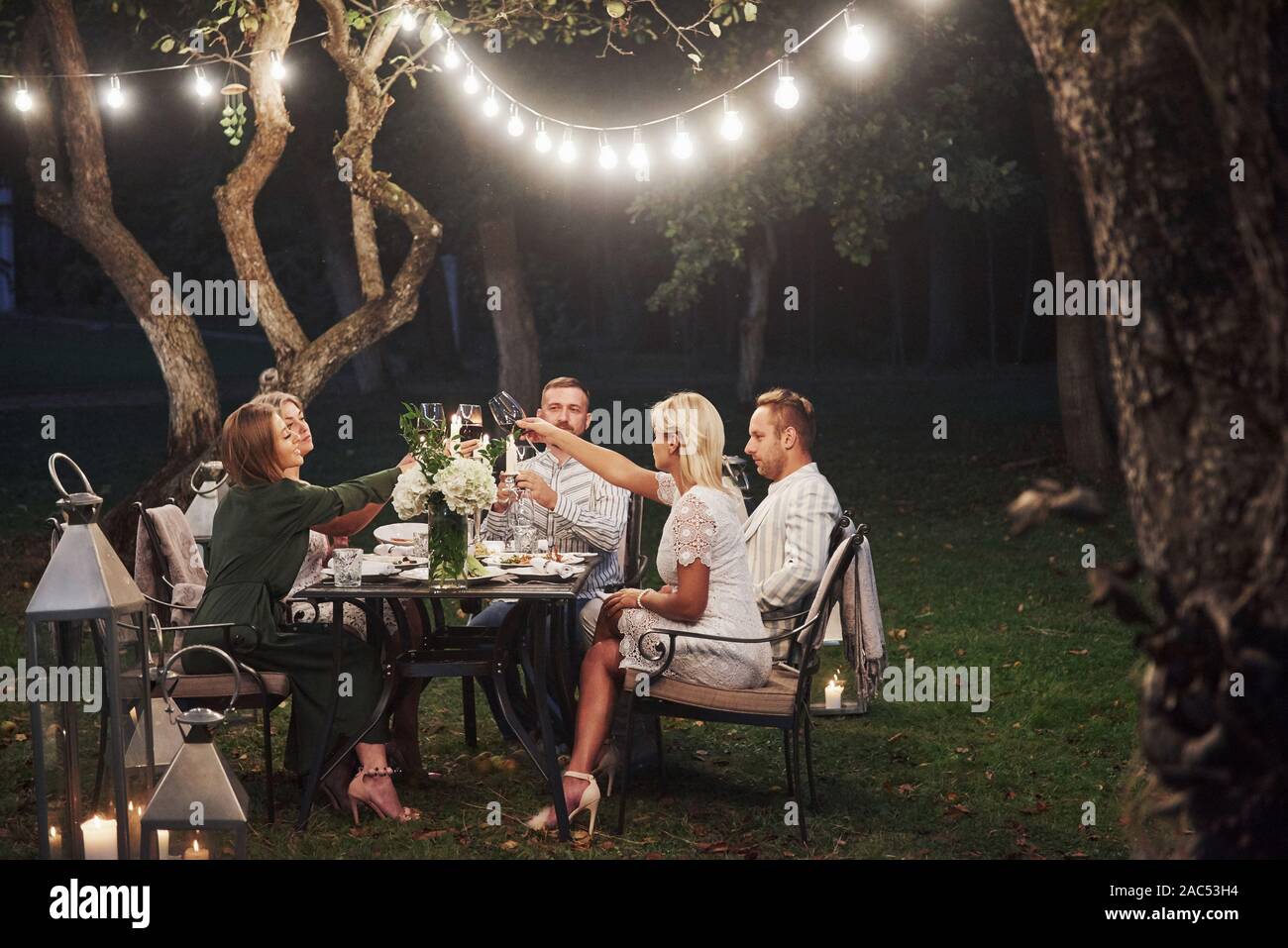 Good lighting. Evening time. Friends have a dinner in the gorgeous outdoor place Stock Photo