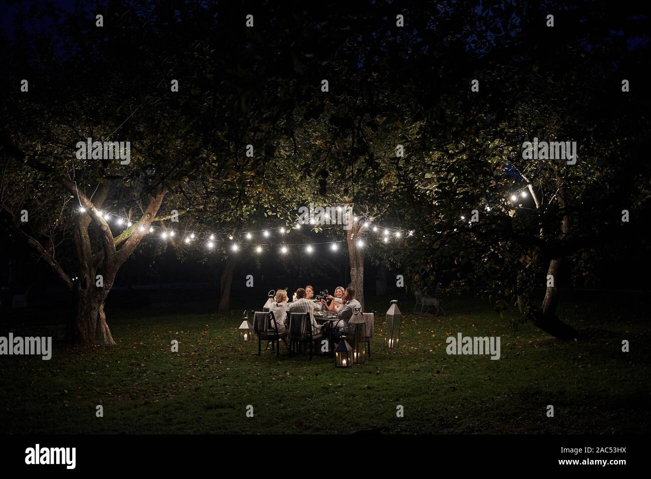 Happy together. Evening time. Friends have a dinner in the gorgeous outdoor place Stock Photo