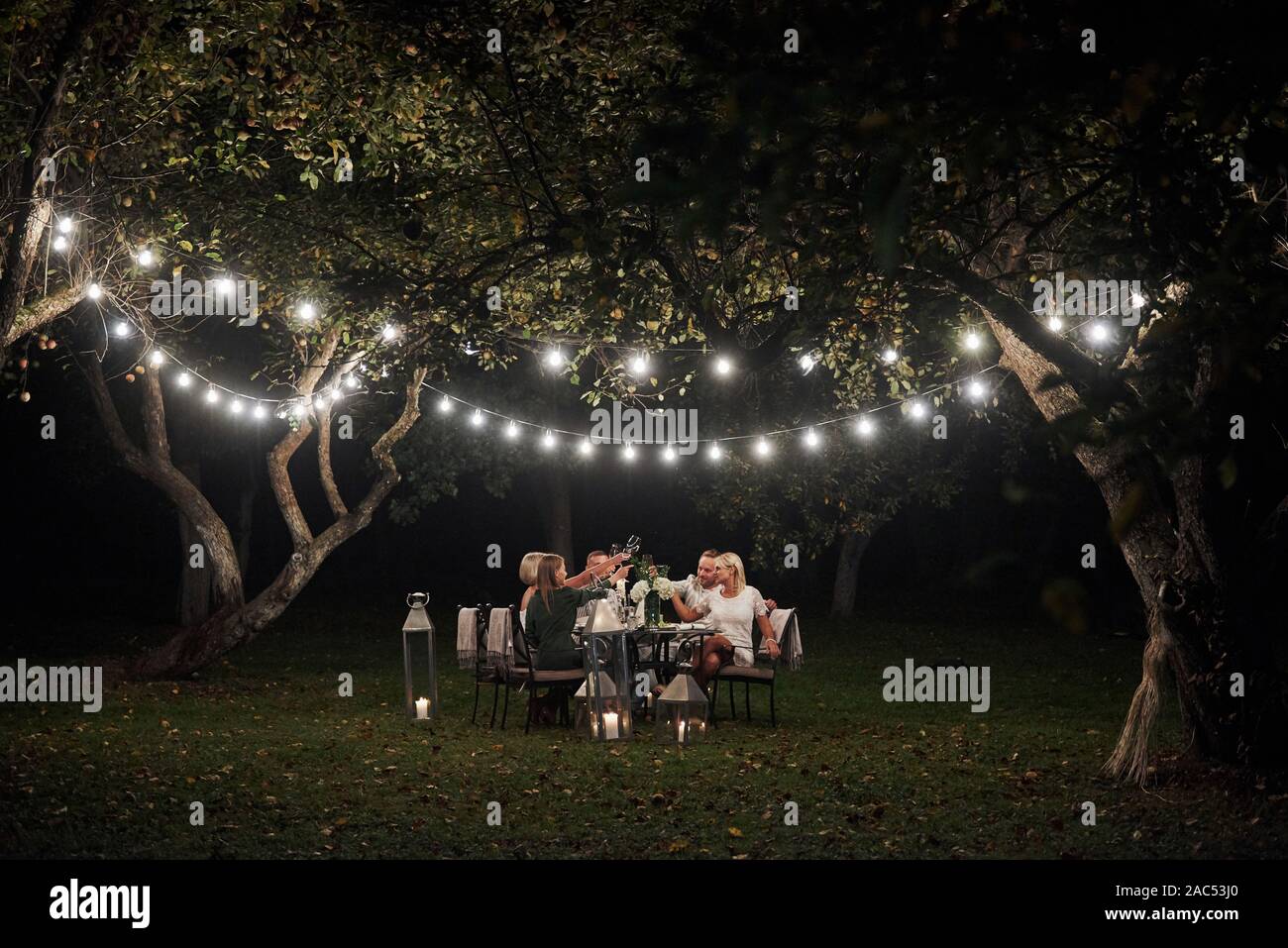 How was your last dinner passed. Evening time. Friends have a dinner in the gorgeous outdoor place Stock Photo