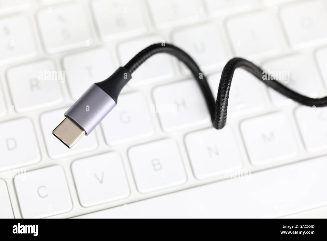 Usb type c cable against laptop keyboard background. Stock Photo