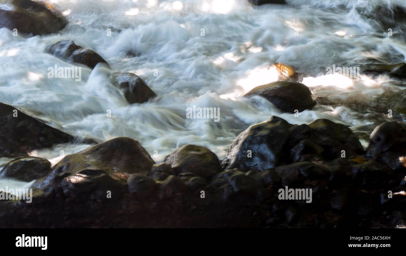 Waves tumble over the rocky shore of Onomea Bay, seen while walking a trail within Hawaii Tropical Botanical Garden in Papa'ikou near Hilo, Big Island Stock Photo