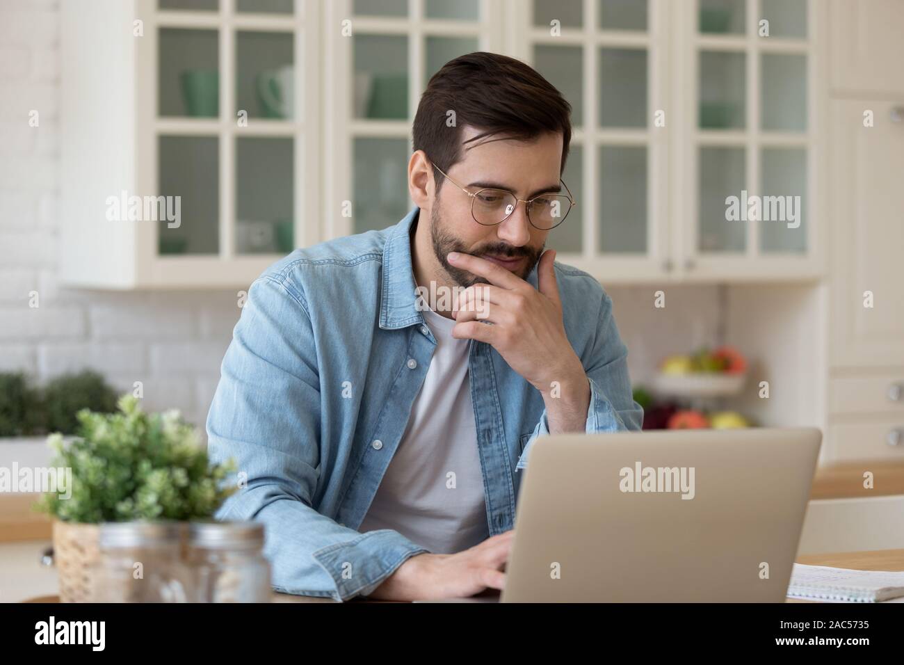 Young guy using laptop notebook sit at home table Stock Photo