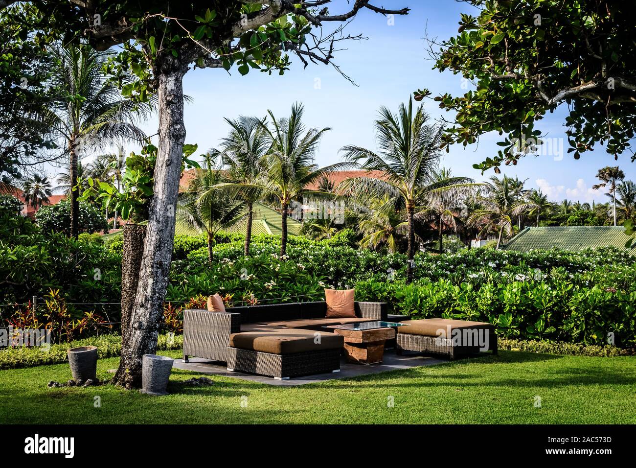 outdoor garden seating in a garden with pillows and many trees Stock