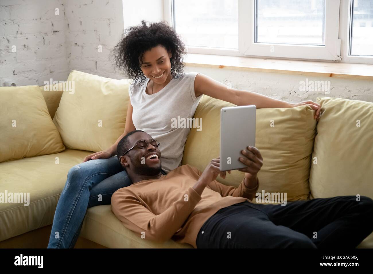 Happy Mixed Race Couple Relax On Couch In Living Room Watch Movie