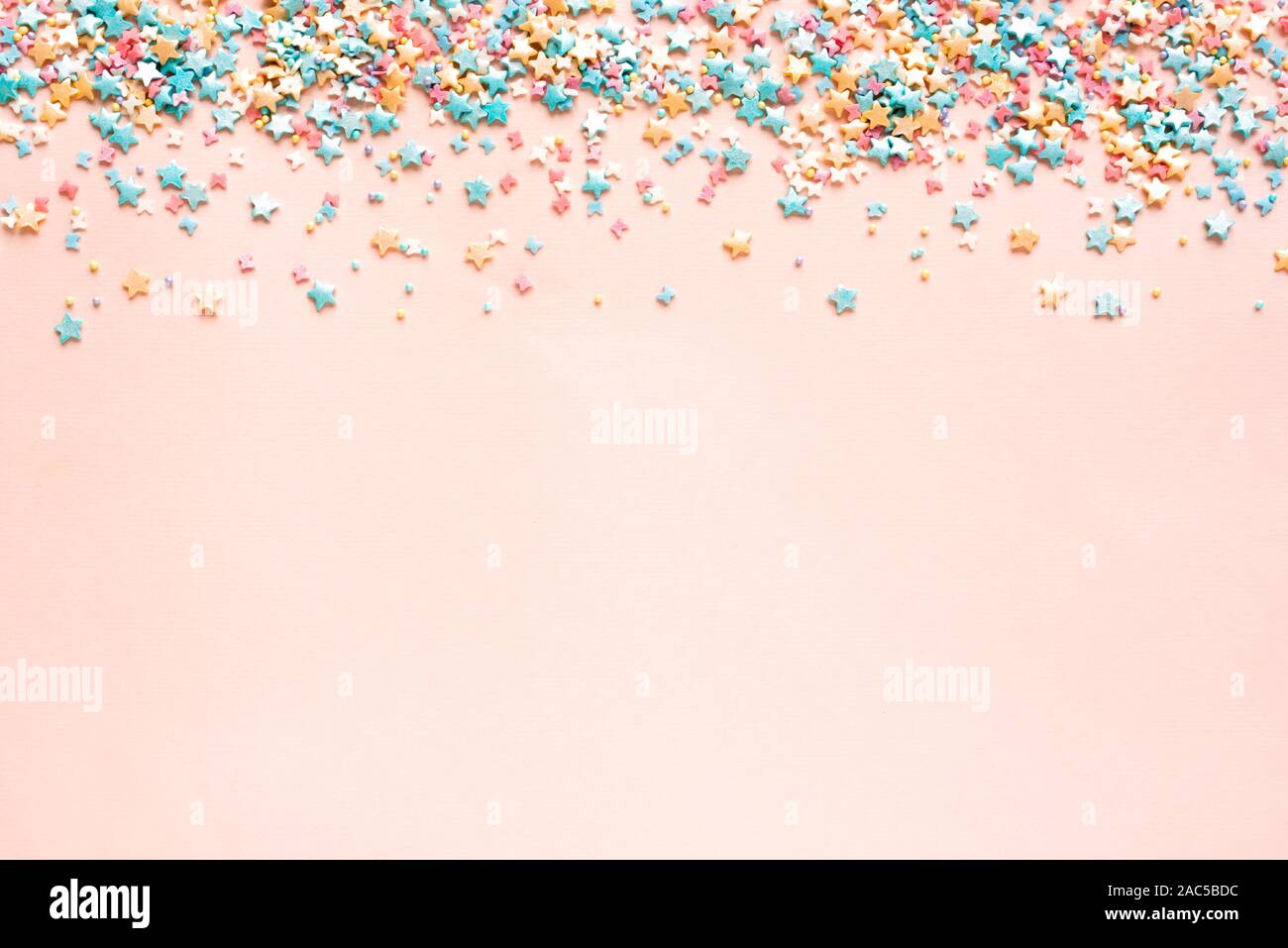 Colorful Pastel Sprinkles on pink background, top view, copy space