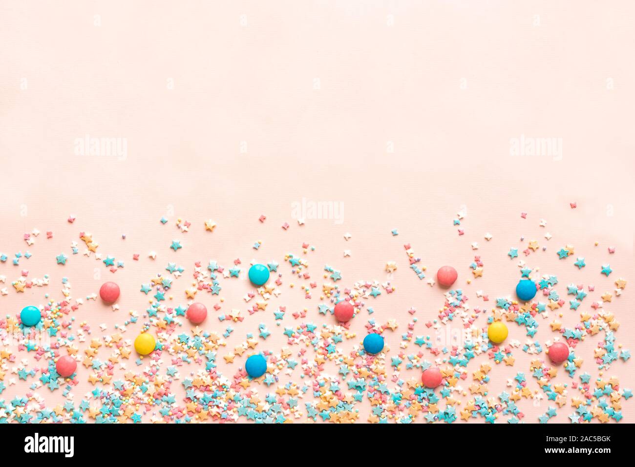 Colorful Pastel Sprinkles on pink background, top view, copy space