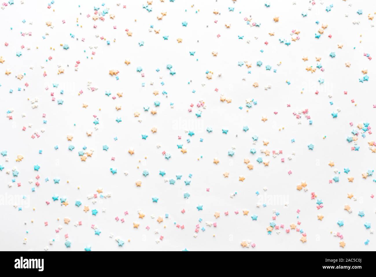 Colorful Pastel Sprinkles on white background, top view, flat lay. Sweet cake pastry ingredient, holiday birthday concept, creative seamless pattern. Stock Photo