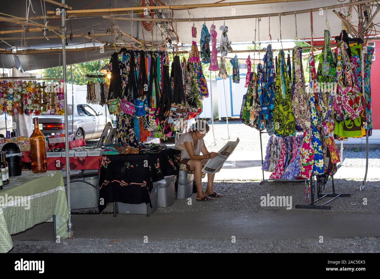 A local fabric vendor reads a newspaper at the Hilo Farmers Market on