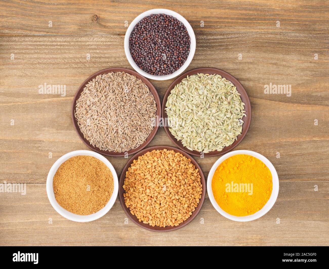Mustard seeds, cumin, fennel, fenugreek, masala, turmeric on brown