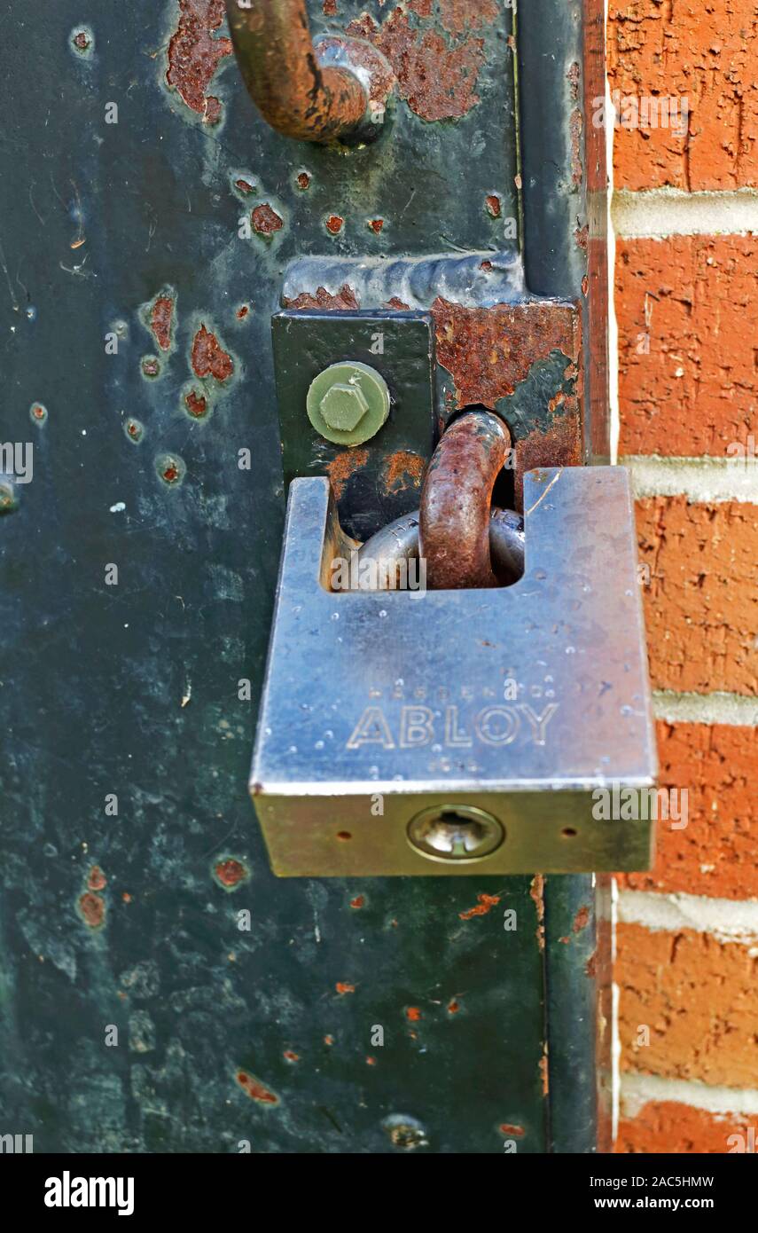 A heavy duty weatherproof padlock on an outdoor strong door. Stock Photo