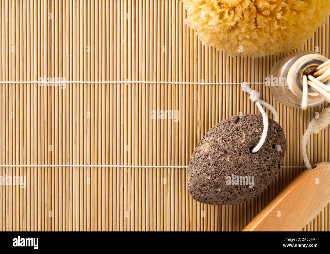 Black lava pumice stone with natural spa or bath utensils used for peeling or callused skin removal on bamboo mat background with copy space Stock Photo