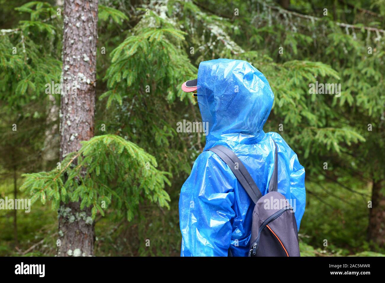 Woman in blue protective polyethylene raincoat agains Stock Photo