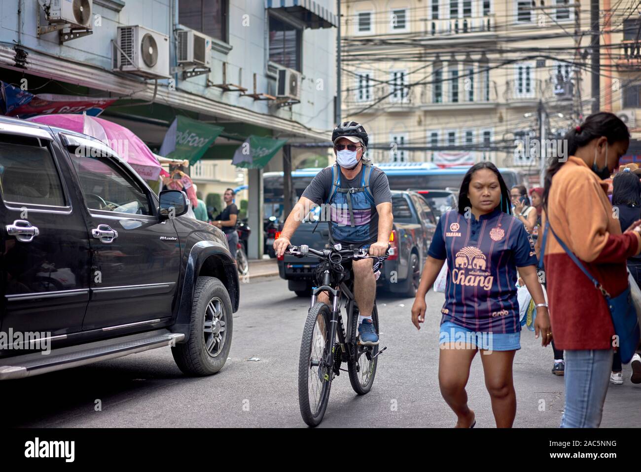 Cyclist wearing an anti pollution face mask  whilst cycling through traffic. Thailand, Southeast Asia Stock Photo