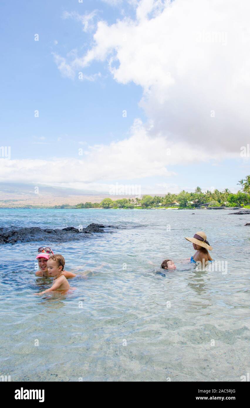 Two local families swim in and explore the tide pools at a beach in