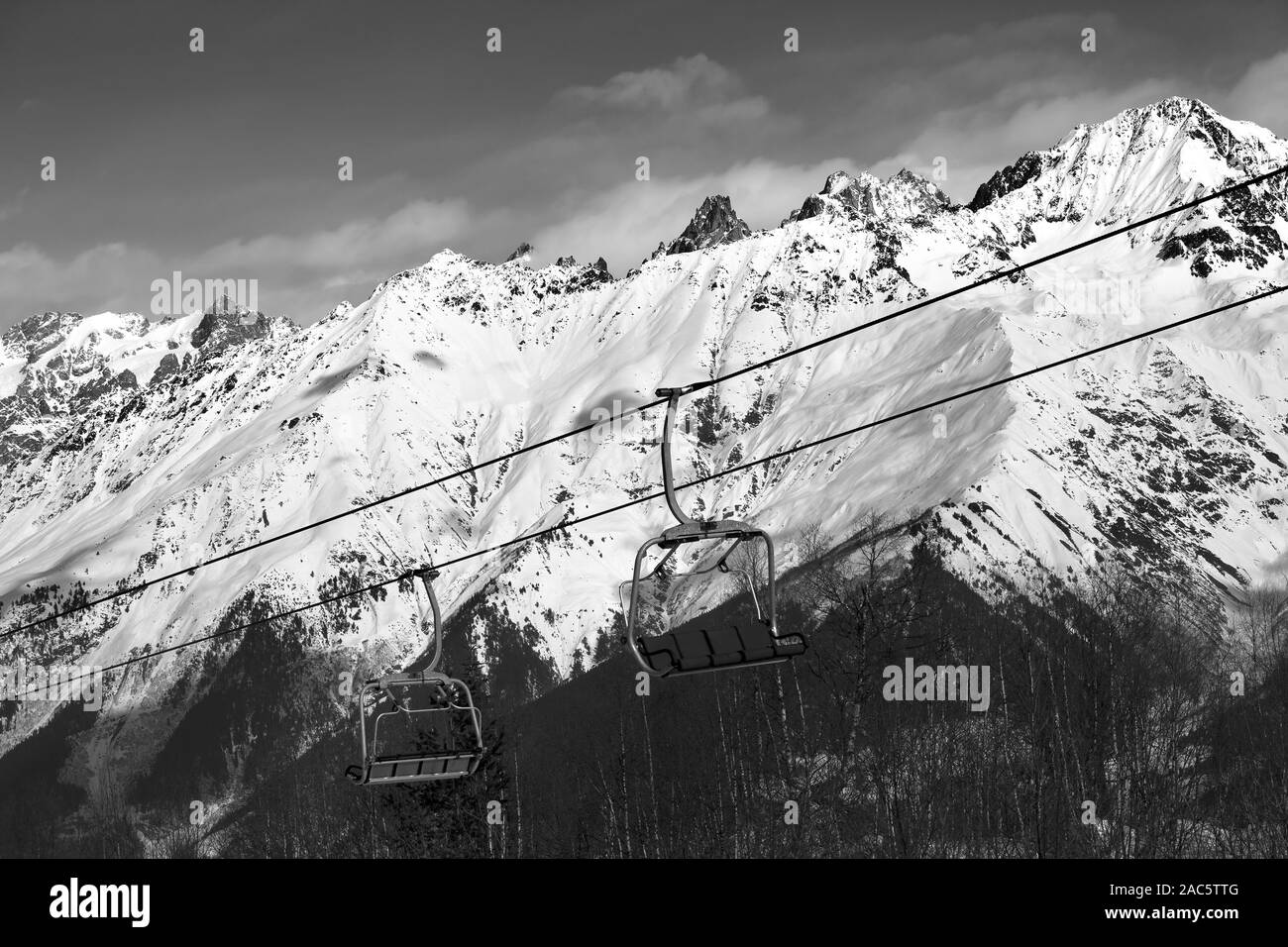 Ski resort with chair lift and snowy mountains at nice sunny day. Caucasus Mountains. Hatsvali, Svaneti region of Georgia at winter. Black and white t Stock Photo