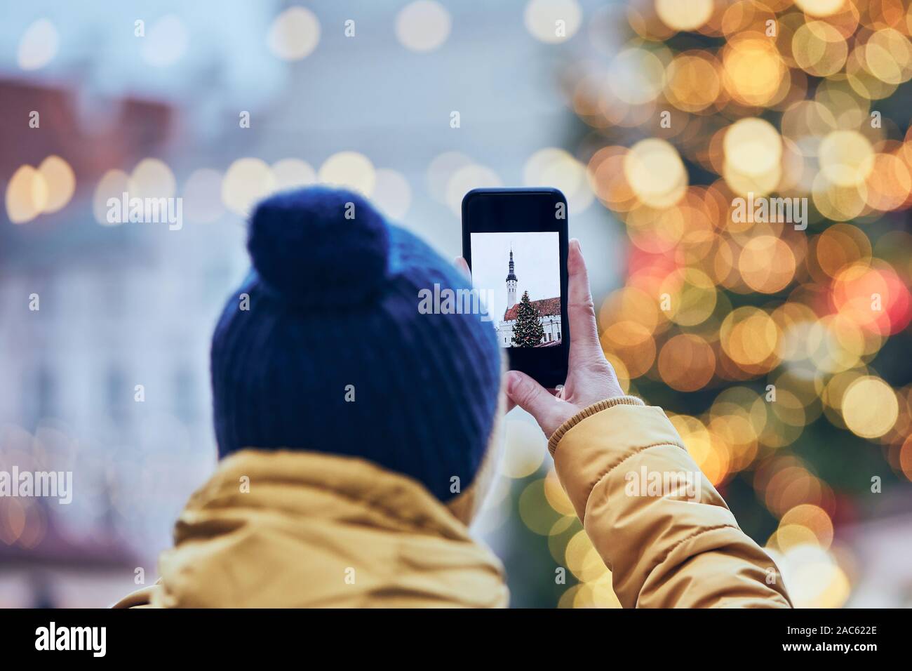 Man with smart phone photographing Christmas tree against Town Hall in Tallinn, Estonia. Stock Photo