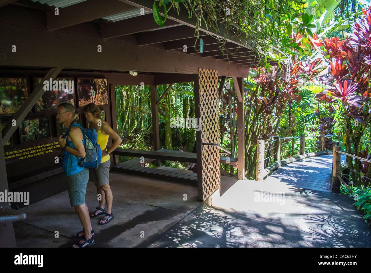 Two tourists read a sign and look at photos of the founders of the Hawaii Tropical Botanical Garden, Papa'ikou, Big Island of Hawaiʻi. Stock Photo