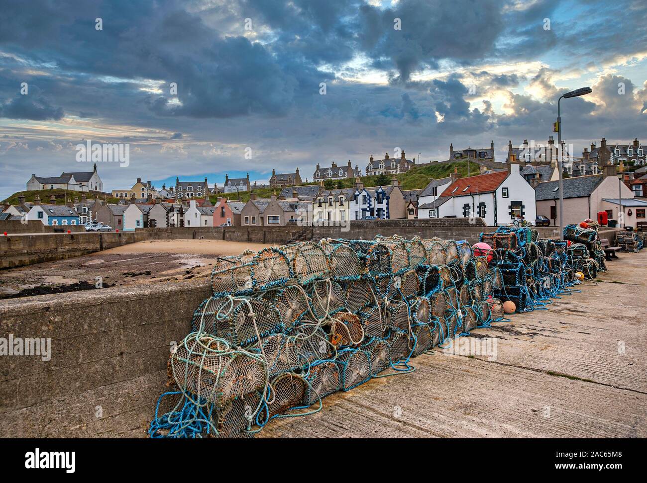 Fishing gear on pier and converted fishing houses in the harbour of Findochty in county Moray North East Scotland Stock Photo