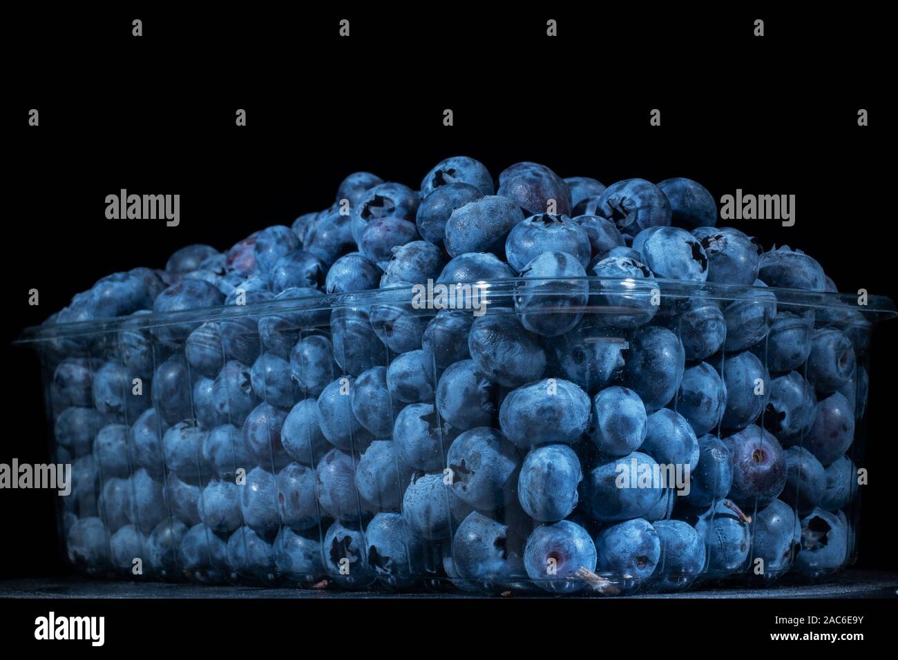 Fresh blueberries in disposable plastic food pack on black background. Close-up of Bog bilberry, bog blueberry, northern bilberry or western blueberry Stock Photo