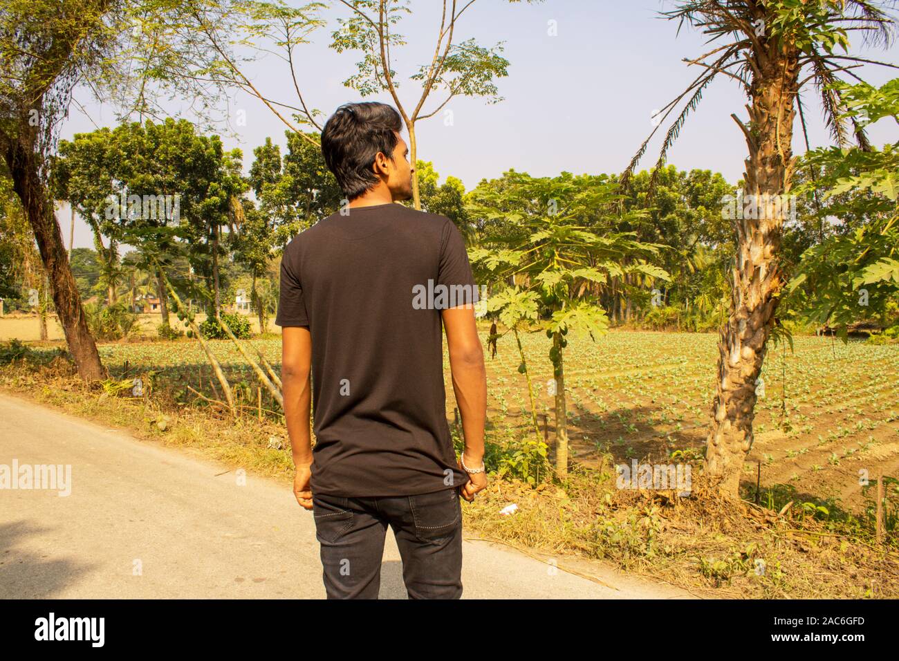 Backside of a young boy wearing black t shirt simple natural get up,  background is nature Stock Photo - Alamy