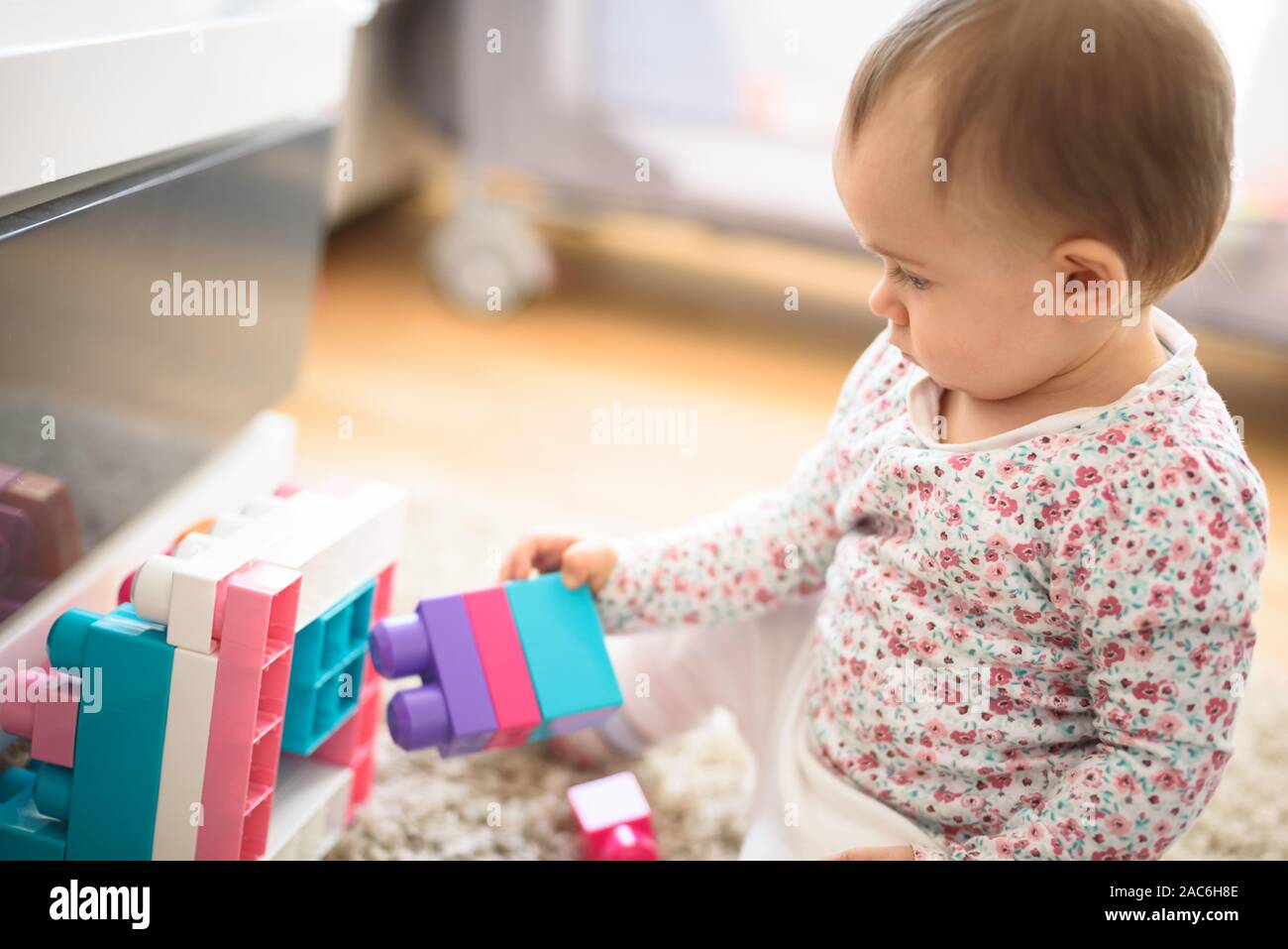 Beautiful baby building with plastic blocks in bright room. Education concept. 6 - 12 month old child. Stock Photo