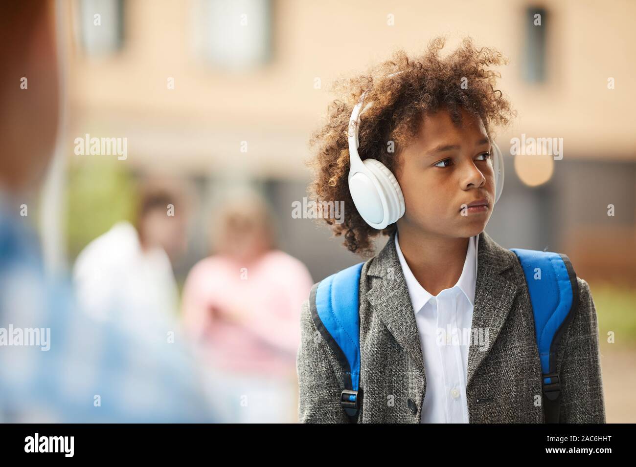 African schoolboy wearing headphones listening to music while walking on the street after school Stock Photo