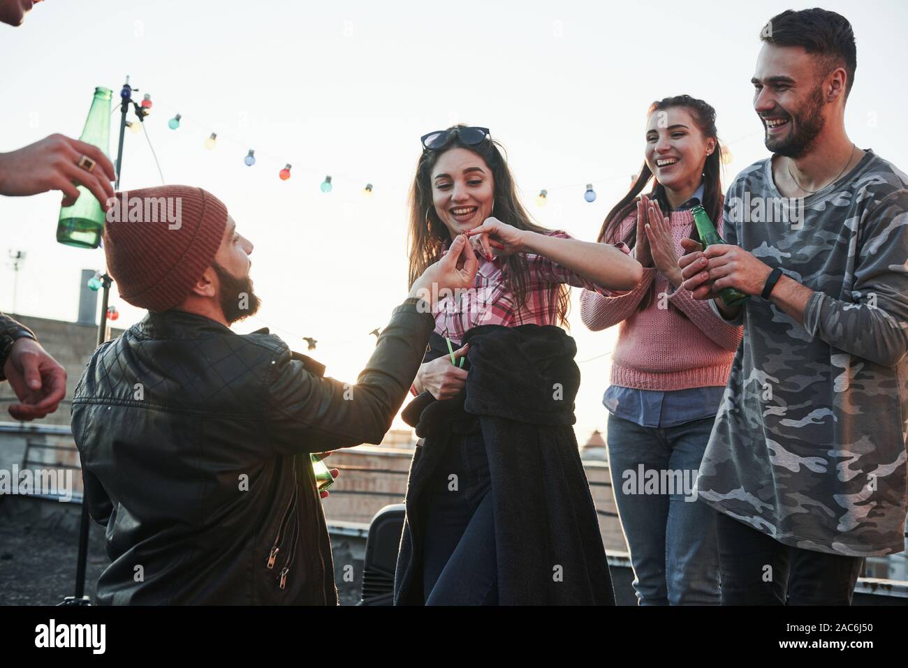 Girl gives her pinky finger. Declaration of love on the rooftop with company of friends Stock Photo