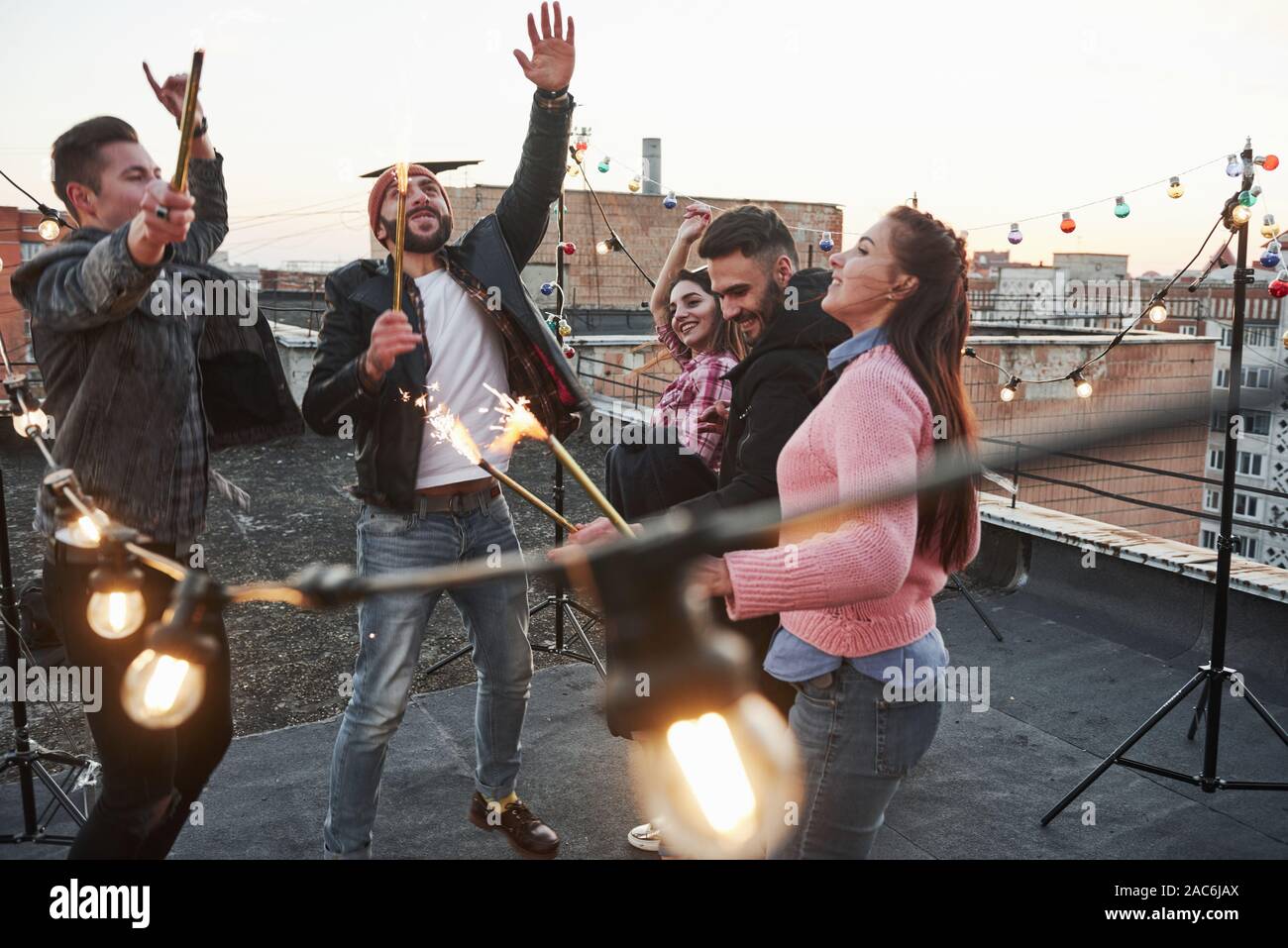 Beautiful people. Playing with sparklers on the rooftop. Group of young beautiful friends Stock Photo