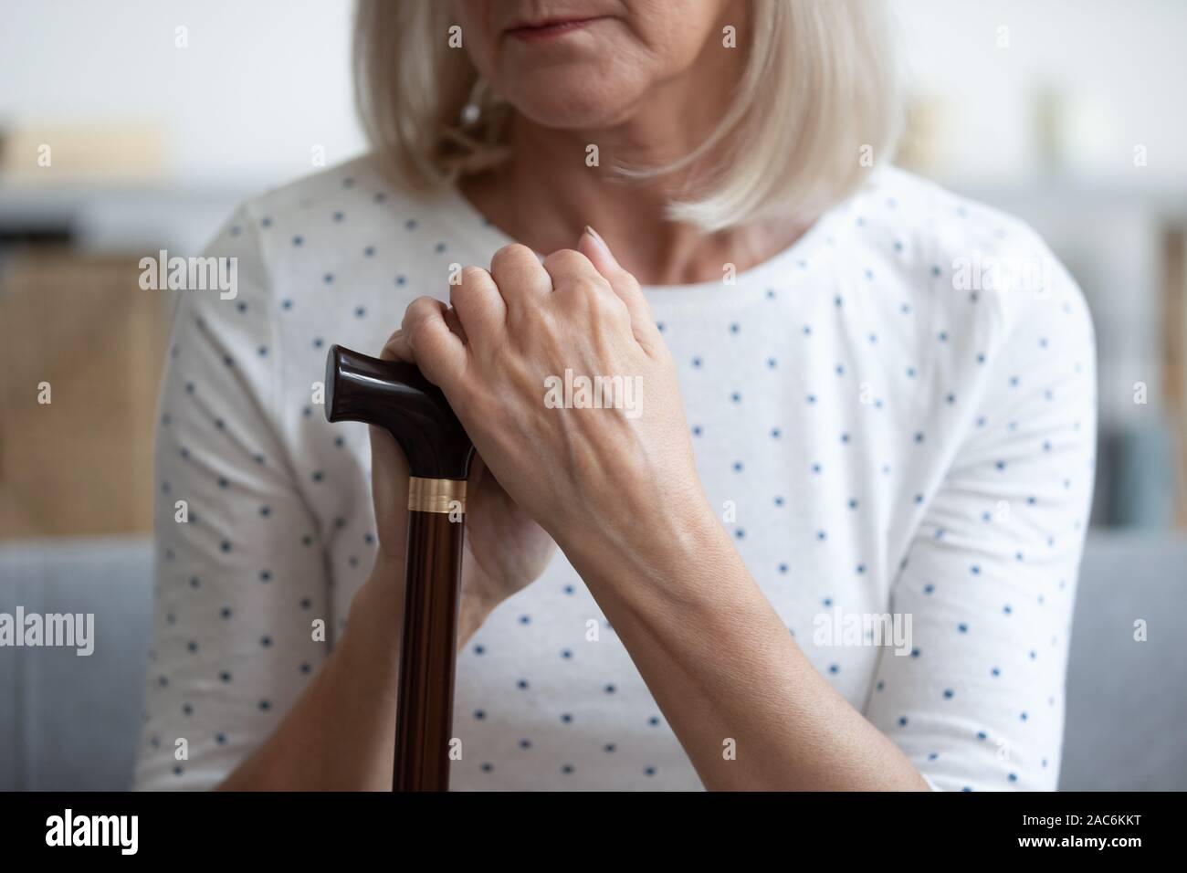 Closeup view cane and arms of depressed disabled retired woman Stock Photo