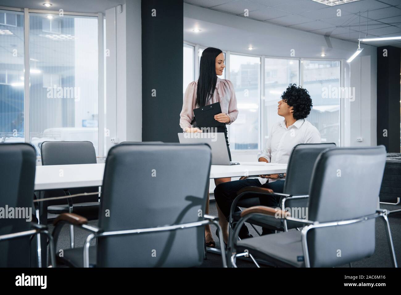 Routine work is not boring for these people. Young professionals. Cheerful coworkers in a modern office smiling when doing their job using laptop Stock Photo