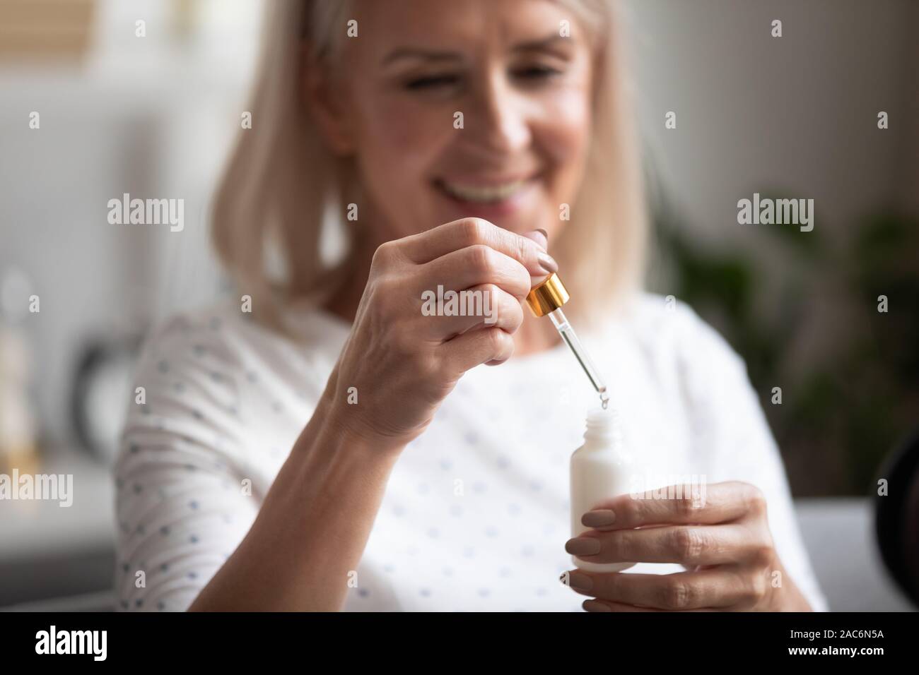 Closeup focus on aged woman hands holding face serum bottle Stock Photo