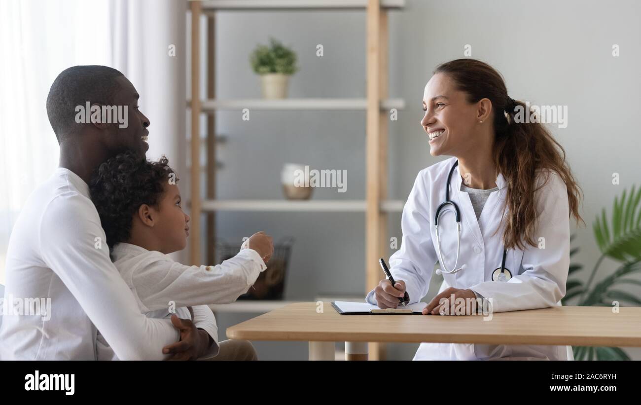 Happy african american man visiting friendly female pediatrician with son. Stock Photo