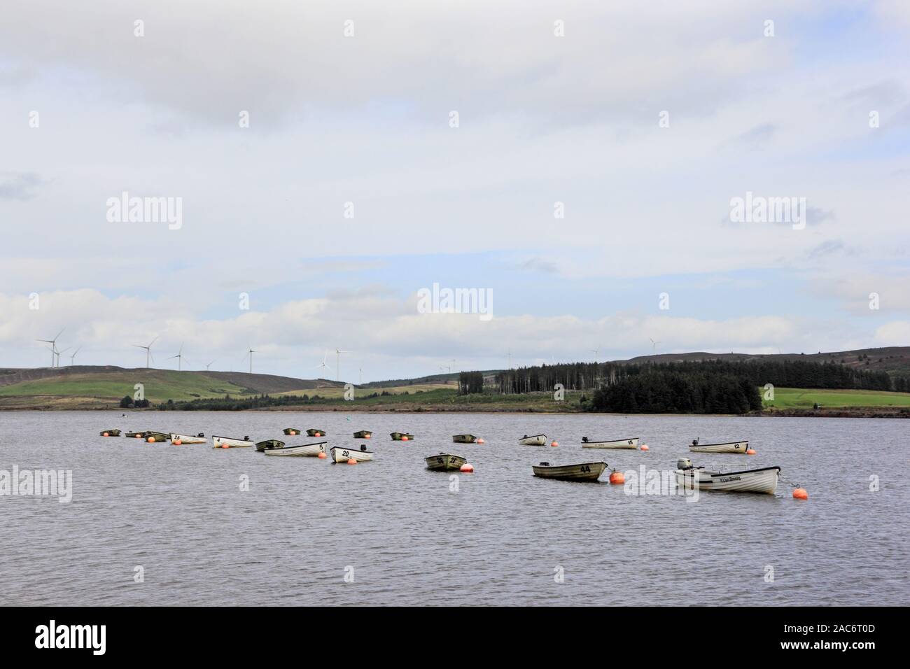 Rowing boats moored on Llyn Brenig Reservoir, with Wind Farm in distance Stock Photo
