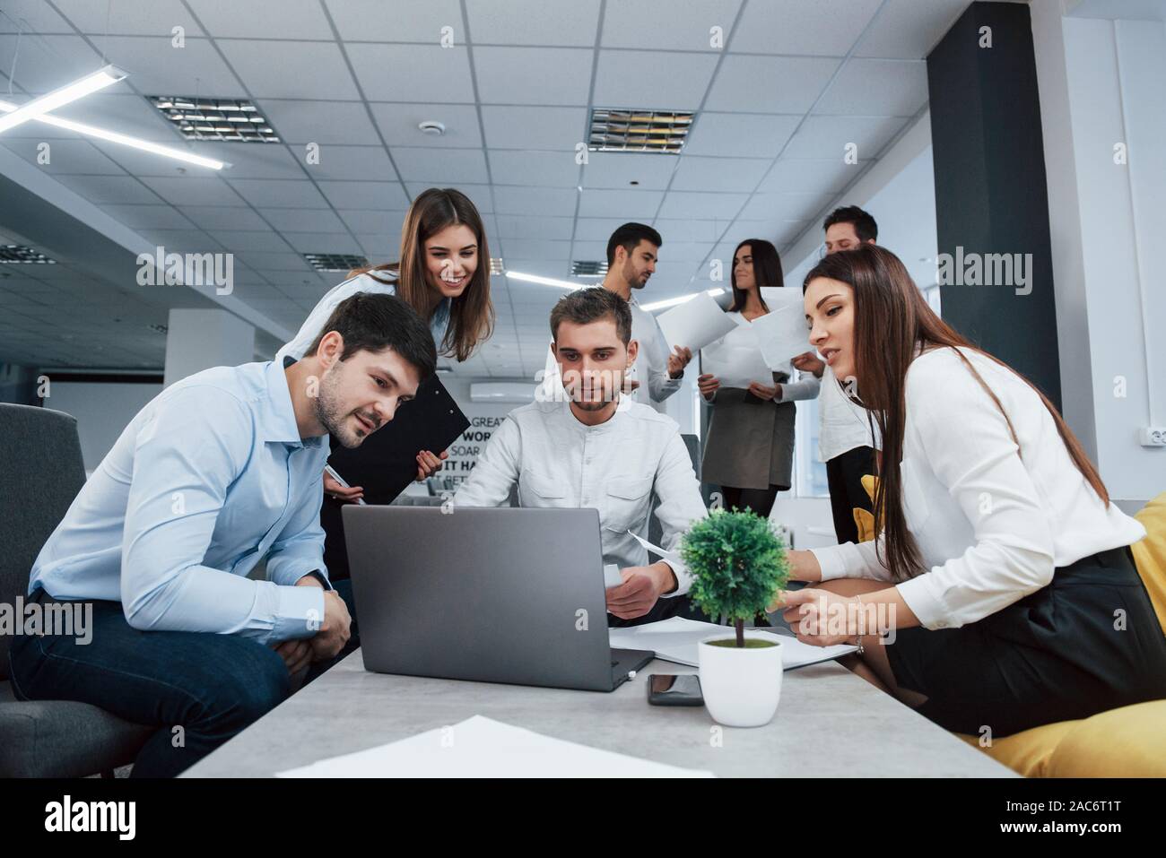 Working with laptop. Group of young freelancers in the office have conversation and smiling Stock Photo