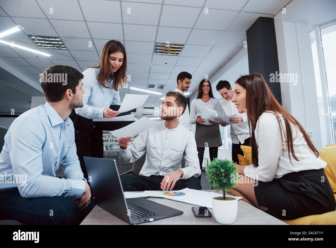 Working but fun atmosphere. Group of young freelancers in the office have conversation and smiling Stock Photo