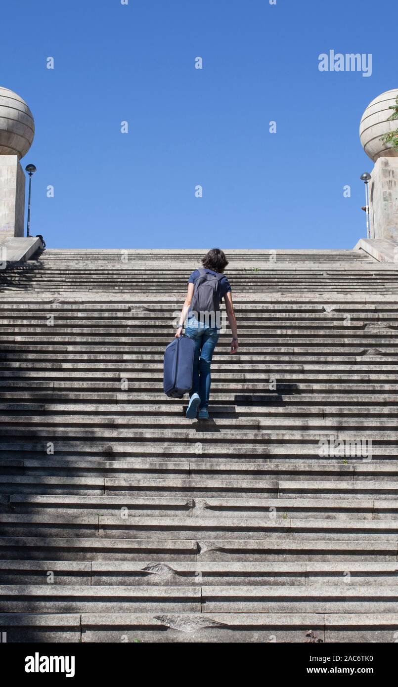 Young tourist woman going up the stairs with her heavy suitcase. Accessibility barriers of historic districts concept Stock Photo