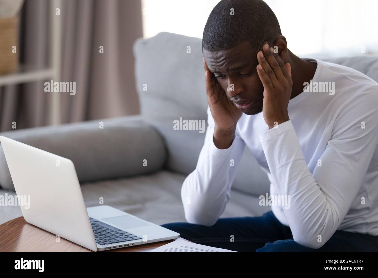 Tired stressed young african american guy massaging temples. Stock Photo