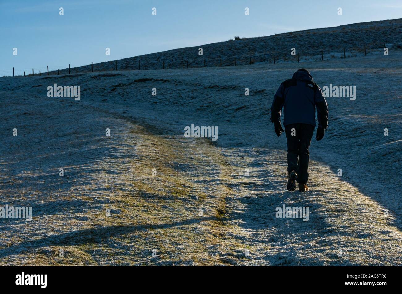 Lammermuir Hills, East Lothian, Scotland, UK. 1st Dec, 2019. UK Weather: the landscape in the moorland is covered in frost with the temperature around freezing on a beautiful sunny Winter day. A man wearing Winter clothing walks uphill on a frozen path Stock Photo