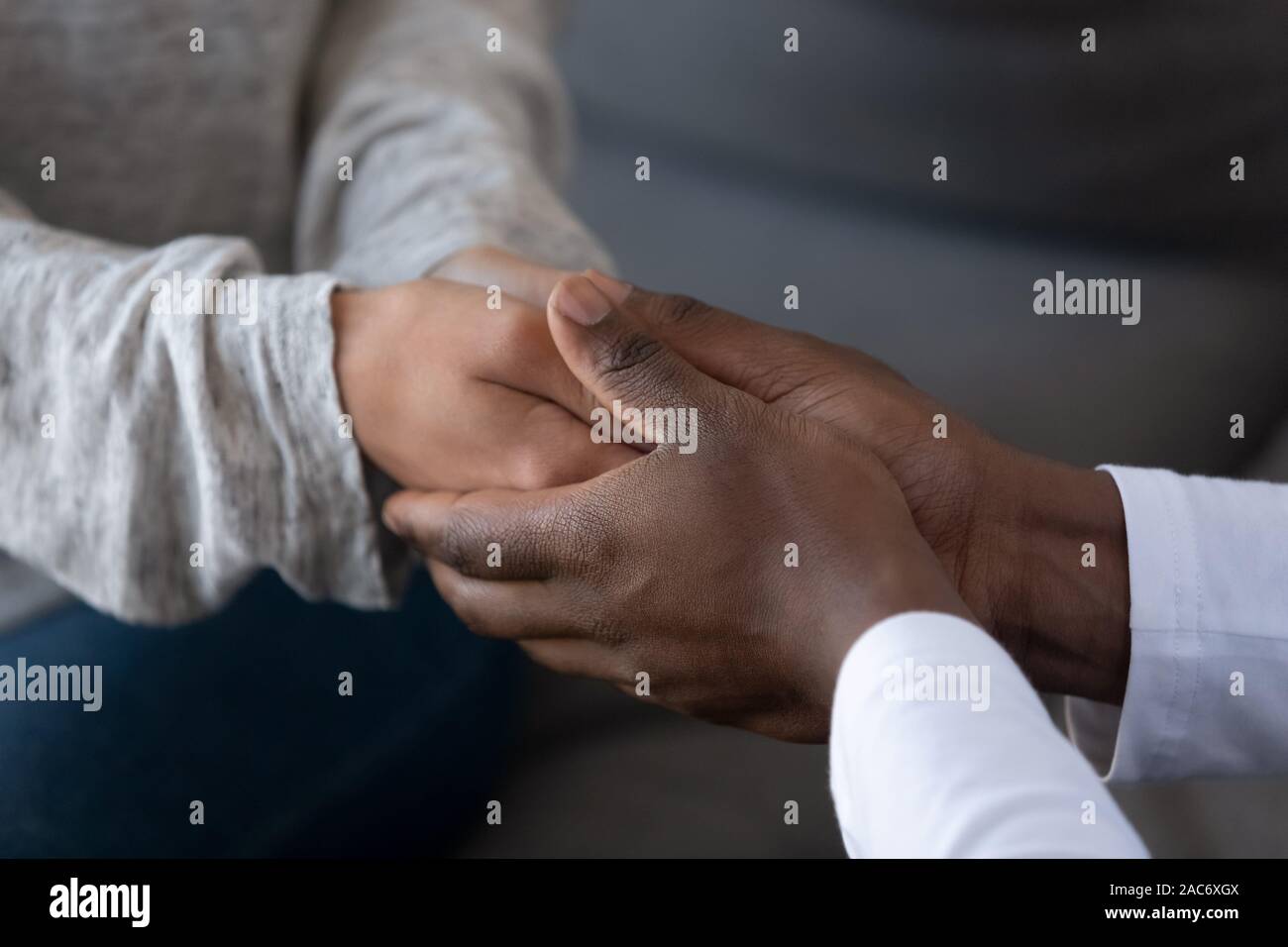 Young african american guy holding hands of woman, giving support. Stock Photo