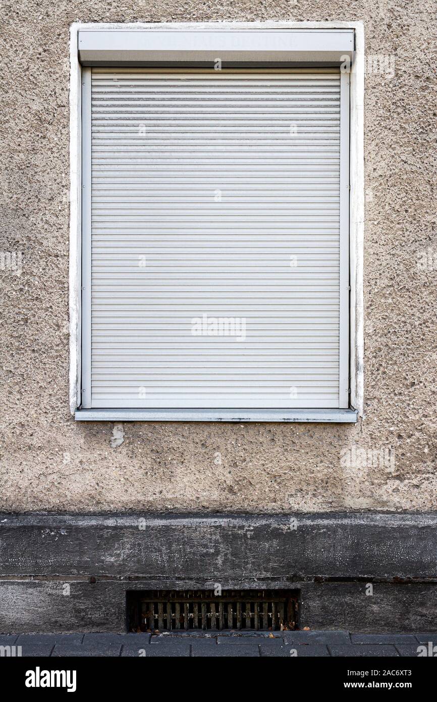 Old gray wall with a window protected by blinds Stock Photo
