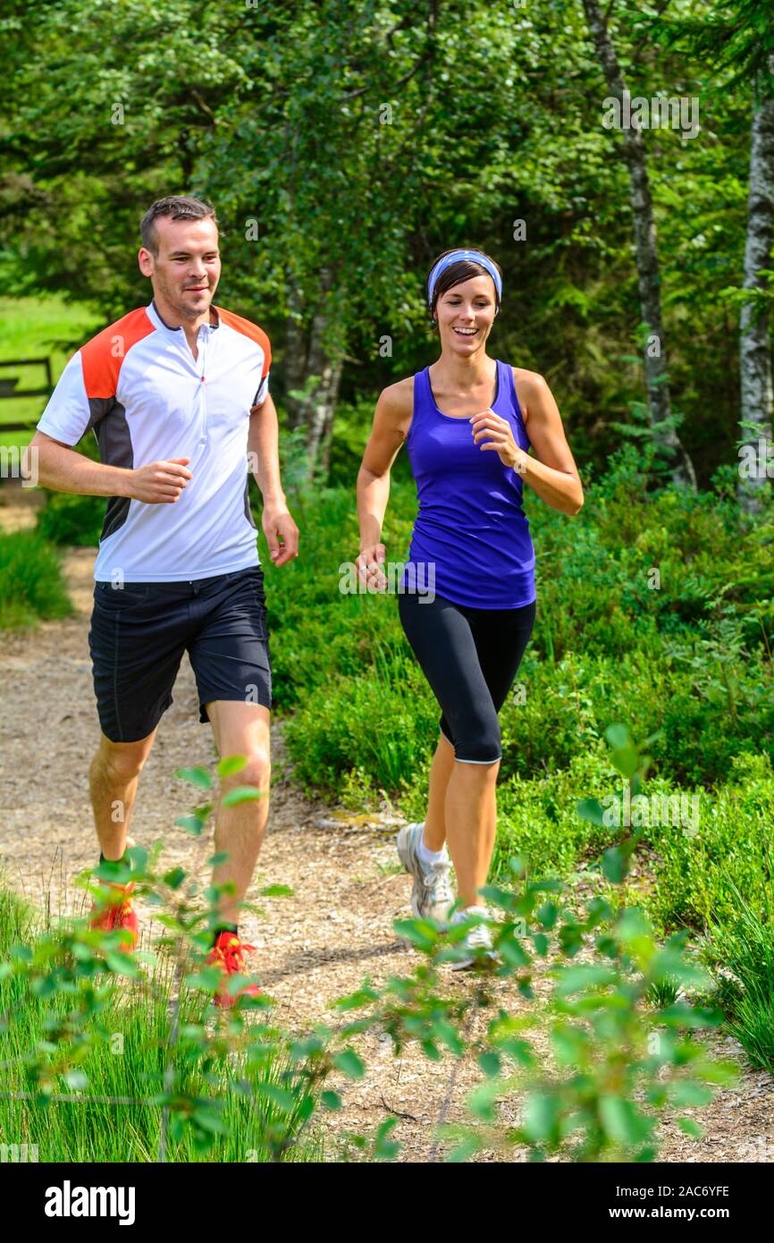 Young couple jogging in forest - strenuous workout in summertime Stock Photo