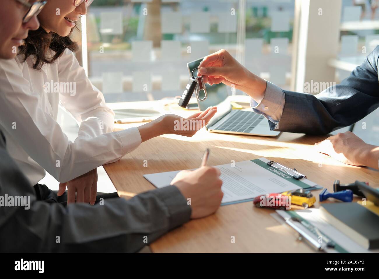 Dealer Salesman Giving Car Key To New Owner Client Signing