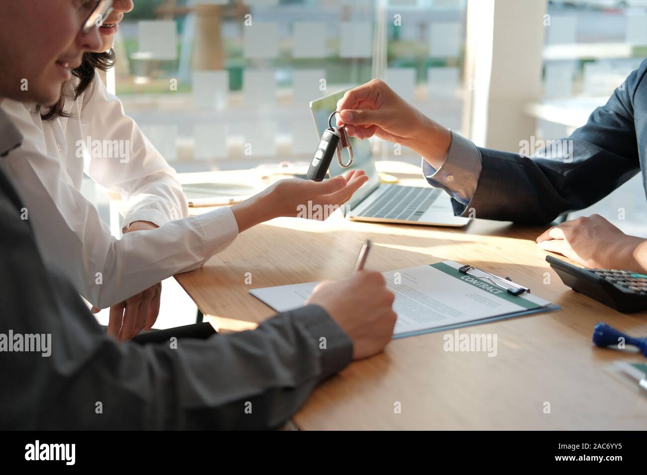 Dealer Salesman Giving Car Key To New Owner Client Signing