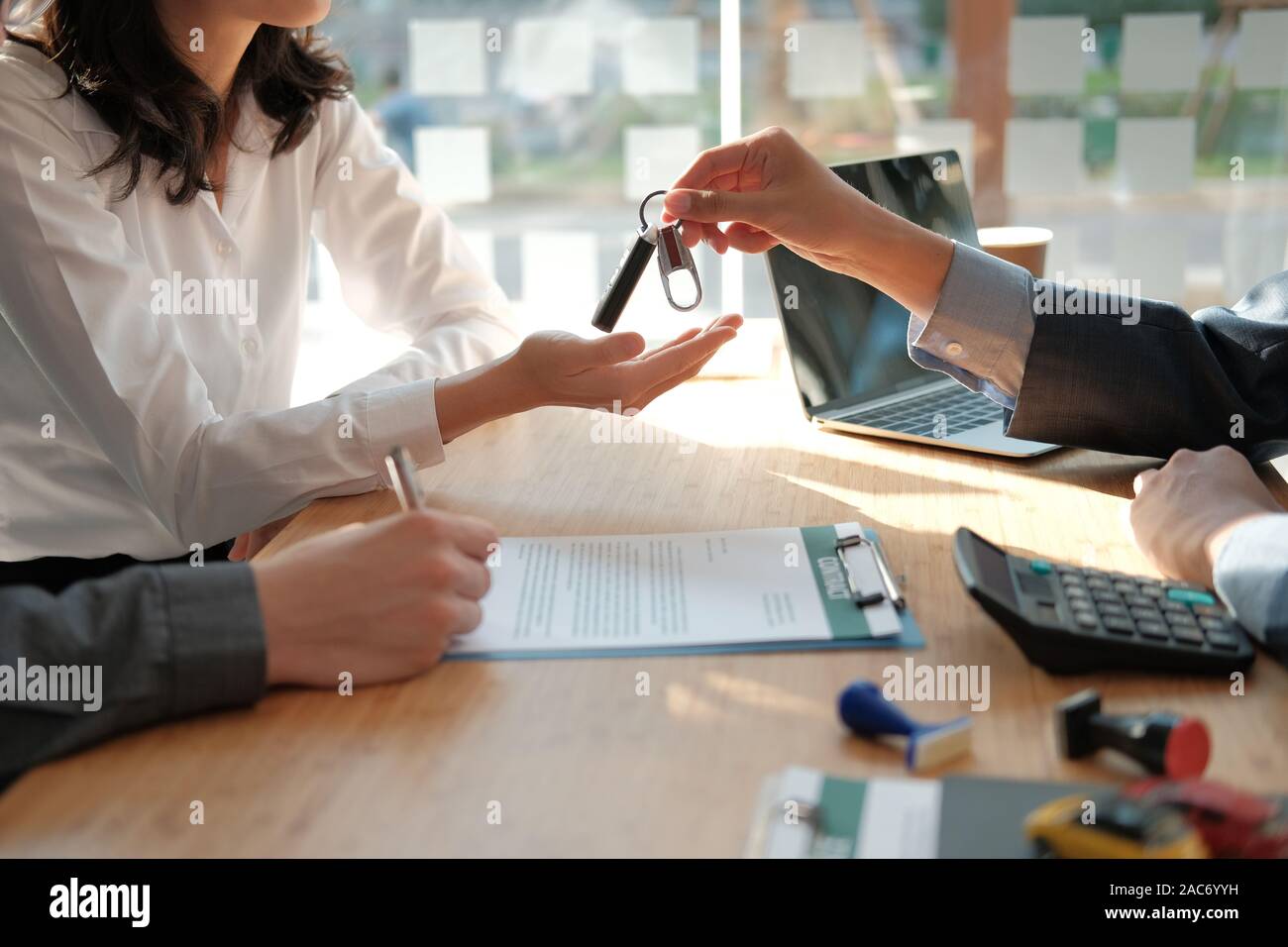 Dealer Salesman Giving Car Key To New Owner Client Signing