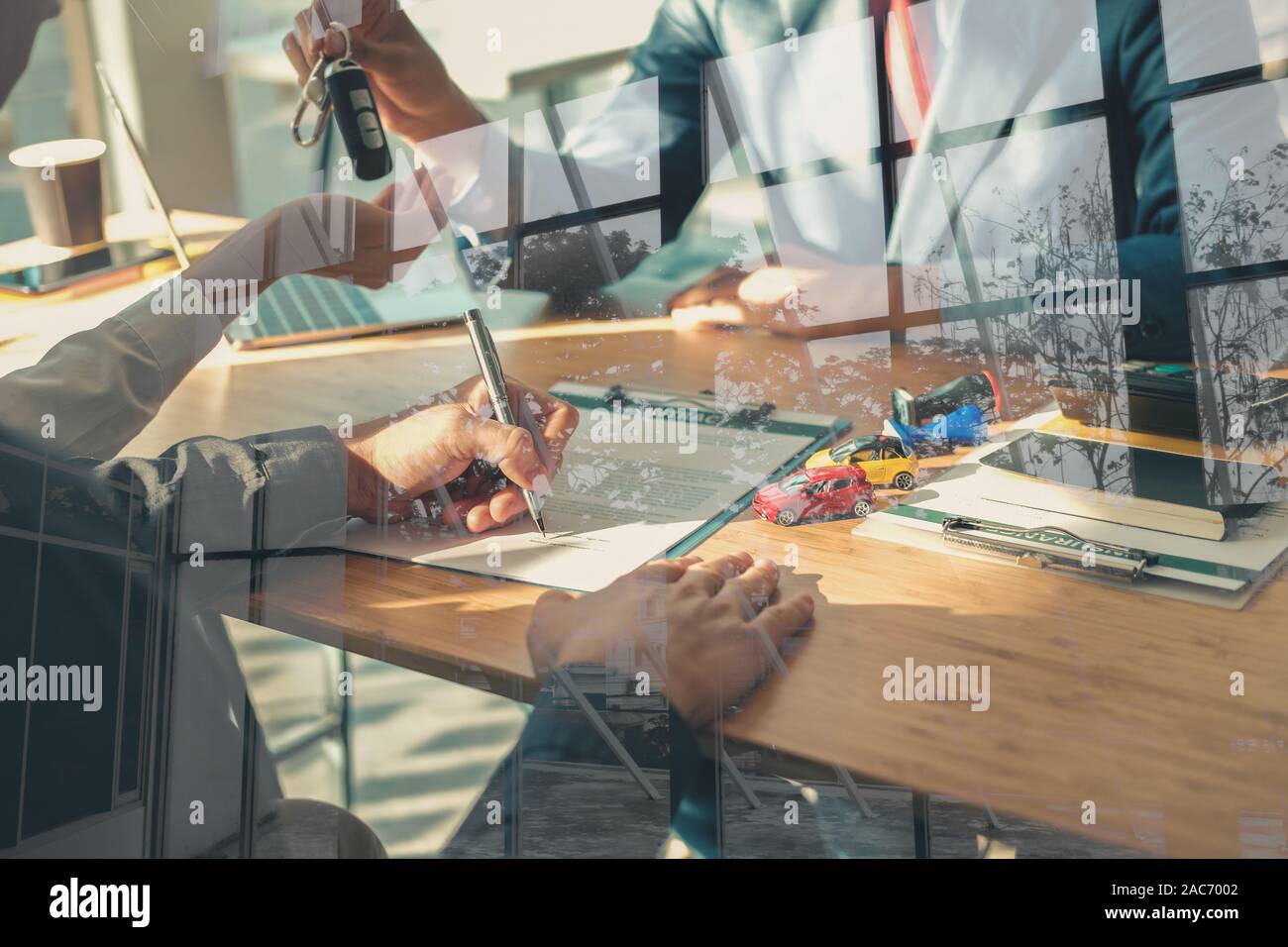 dealer salesman giving car key to new owner. client signing ...