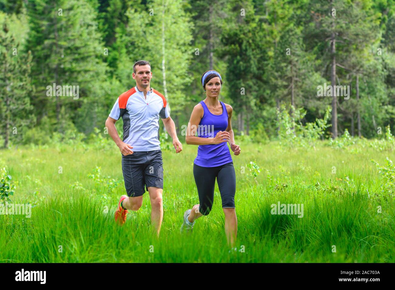 Young couple jogging in forest - strenuous workout in summertime Stock Photo